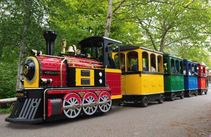The Northern Lights Express train carrying riders through a tree-lined park