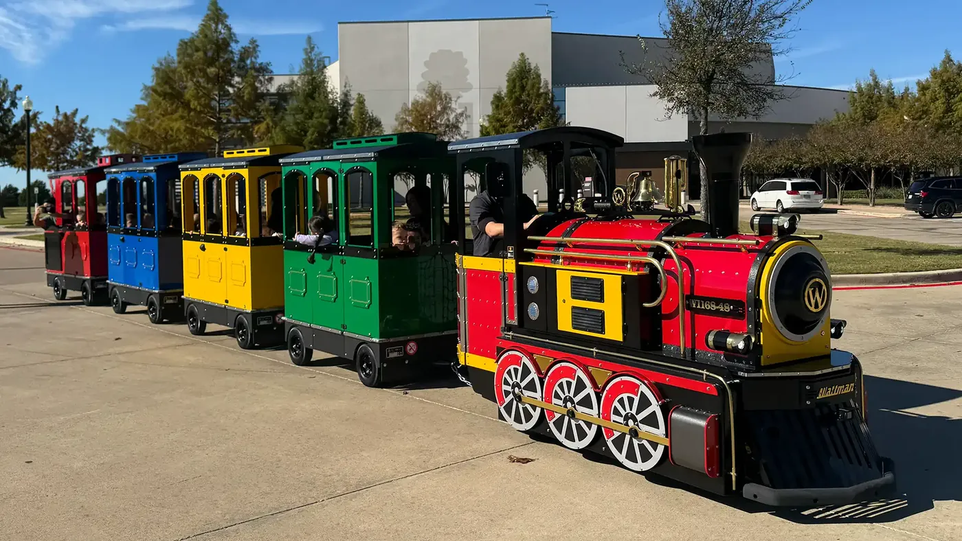 The full Northern Lights Express trackless train: a red locomotive pulling green, yellow, blue, and red passenger cars